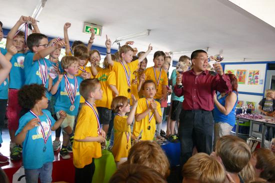 De schakers van De Spits (gele shirts) krijgen de beker uitgereikt door Dharma Tjiam, jeugdleider van de KNSB.